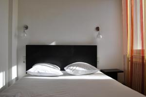 卡斯泰尔诺达里卡苏莱逸轩酒店的床上的2个枕头和黑色床头板