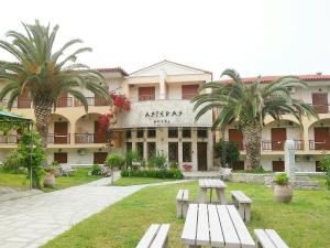 卡尼奥提Asteras hotel的一座有长椅的建筑,前面有棕榈树