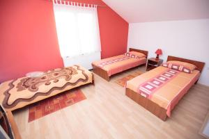比尔杰Guesthouse Capistro的红色墙壁的房间里设有三张床