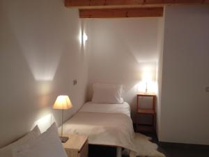 塔卢瓦尔180度湖景别墅的一间小卧室,配有一张白色的床和两盏灯