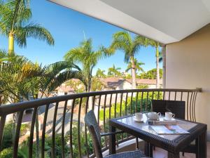 卡伦德拉Oaks Sunshine Coast Oasis Resort的棕榈树阳台的桌椅