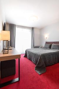 德鲁斯基宁凯辛帕提亚酒店的一间卧室配有一张床,铺有红色地毯