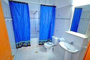 Megálon ChoríonNitsa's Apartments的浴室设有蓝色窗帘、卫生间和水槽。