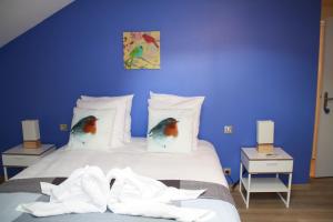 Niaux尼奥斯旅馆的蓝色卧室配有一张床铺,枕头上有两只鸟