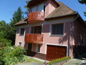 拜赖焦新村Liget Szálláshely的粉红色的房子设有阳台和车库