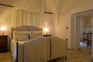 圣维托诺曼Masseria Pagliamonte Ortensia的一间卧室配有一张床和一张带台灯的桌子