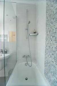 沃特福德Station Suites的带淋浴和盥洗盆的白色浴室
