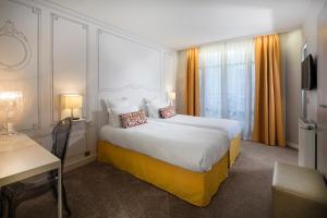 巴黎巴黎伏吉拉尔酒店的酒店客房设有一张大床和一张书桌。
