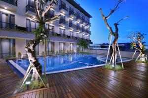 马塔兰ASTON Inn Mataram的一座拥有游泳池和树木的甲板酒店