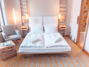柏林柏林布雷多金色郁金香酒店的一张带白色床单的床和一把椅子