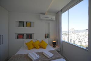 里约热内卢休格公寓式酒店的一间卧室配有一张带黄色枕头的床和一扇窗户