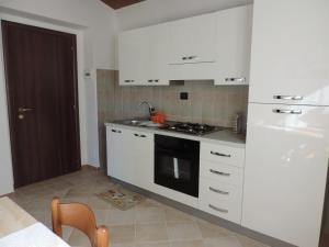 科玛南扎Il Gelso Rosso的厨房配有白色橱柜和炉灶烤箱。