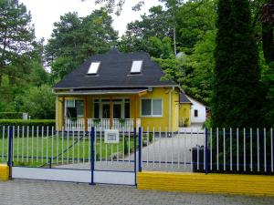 鲍洛通塞迈什Relax Apartmans的铁栅后面有黑色屋顶的黄色房子