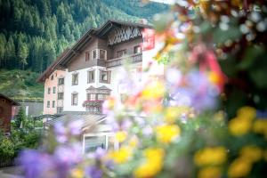 圣安东阿尔贝格Quality Hosts Arlberg - Lärchenhof的山中一座大建筑,前沿有鲜花