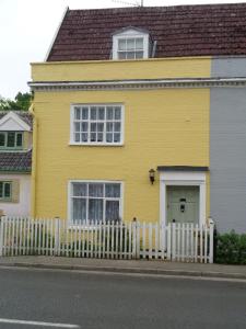 YoxfordMinsmere Cottage的前面有白色围栏的黄色房子
