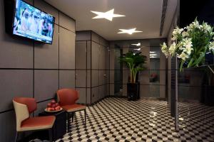 新加坡Hotel 81 Premier Hollywood的一间设有椅子和墙上电视的等候室
