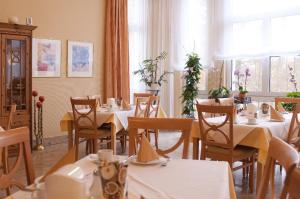 巴特洪堡帕克酒店的一间设有白色桌椅和窗户的用餐室