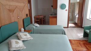 Ollomont歌乐山旅馆的一间设有两张绿色床和厨房的房间