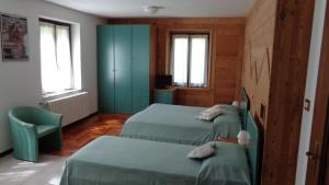 Ollomont歌乐山旅馆的一间卧室设有两张床和蓝色的橱柜