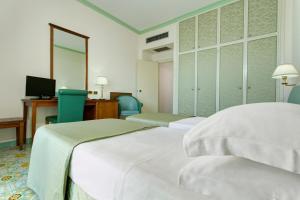 维耶特里劳埃德拜亚酒店的客房设有三张床、一张桌子和一台电脑