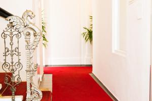 维也纳奧德翁酒店的一条铺有红地毯的走廊和一扇白色的门