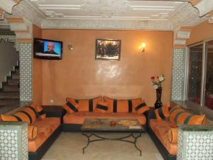 马拉喀什阿尔卡比尔酒店的带沙发的客厅和墙上的电视