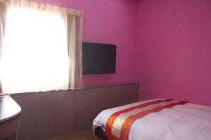 垦丁大街文风小筑的一间卧室设有粉红色的墙壁、一张床和电视