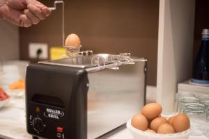 西尔米奥奈H2o住宿加早餐旅馆的一个人在烤面包机的上面拿着鸡蛋