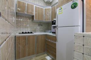 布赖代Dorrat Al Nakheel Chalet的厨房配有木制橱柜和白色冰箱。