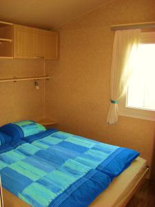 ŠempasMobilehouse & Camping Lijak的一间卧室配有一张蓝色的床和窗户