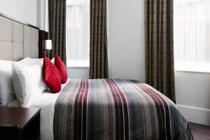 伦敦特拉法加广场豪华酒店的配有红色枕头的床的酒店客房