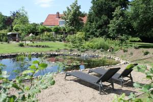 温特斯韦克Boutique Hotel Nieuw Beusink的池塘前的一张野餐桌和两把椅子