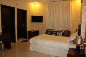 阿尔布亚米Dar Al Khaleej Hotel Apartments的酒店客房设有床、桌子和电视。