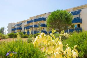 拉卡诺Residence Lacanau Bleu Marine - maeva Home的花园中带蓝色阳台和鲜花的建筑