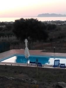马尔萨拉Panorama Casa Vacanze的一个带两把椅子和白色遮阳伞的游泳池