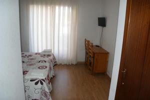 纳瓦莱诺Hostal La Tablada的一间卧室设有两张床、一个梳妆台和窗户。