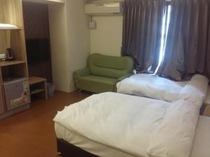 斗六市凯登商务旅馆的酒店客房,配有一张床和一把绿色椅子