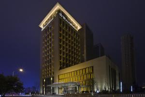 沈阳沈阳富力万达文华酒店的一座高大的建筑,晚上有黄色的灯光