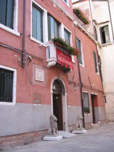 威尼斯Guesthouse Ca' San Marcuola 1的前面有两座雕像的红色建筑