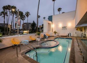 洛杉矶肯尼 - 威尼斯海滩酒店的酒店游泳池设有椅子,酒店大楼