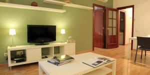 巴塞罗那那不勒斯阿奎拉公寓酒店的一间客厅,客厅内配有一台电视,位于白色娱乐中心