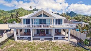 拉罗汤加Seaside Beachfront Villas Rarotonga的海滩上的房子,以群山为背景