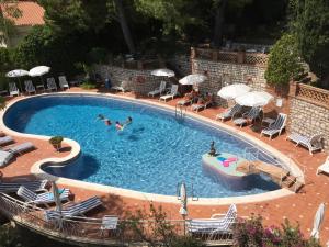 陶尔米纳米迪泰拉尼酒店的游泳池里有人在游泳池里游泳,配有椅子和遮阳伞