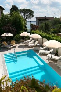 西尔米奥奈塞雷内拉酒店的蓝色游泳池配有遮阳伞和椅子