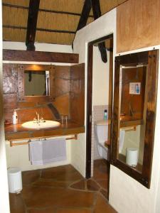 奥马鲁鲁罗迪娜野生山林小屋的浴室配有盥洗盆、镜子和浴缸