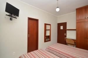坎皮纳斯Villas Boas Hotel的一间卧室配有一张床、一张书桌和一台电视
