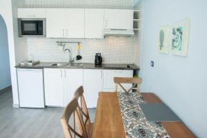 美洲海滩Apartment Las Americas的厨房配有白色橱柜和木桌及椅子