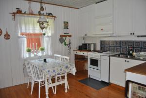 奥萨Orsastuguthyrning-Oljonsbyn的厨房配有白色橱柜和桌椅