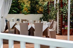 卡梅拉诺康科德酒店的一间设有白色桌椅的餐厅,种植了植物