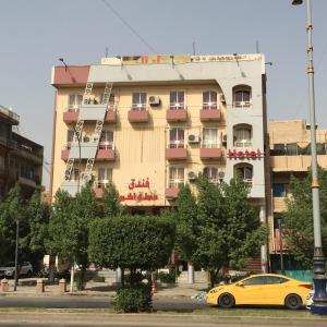 巴格达Dijlat Al Khair Hotel فندق دجلة الخير的停在大楼前的黄色汽车